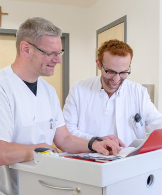 Pfleger im Behandlungszimmer schauen auf eine Mappe