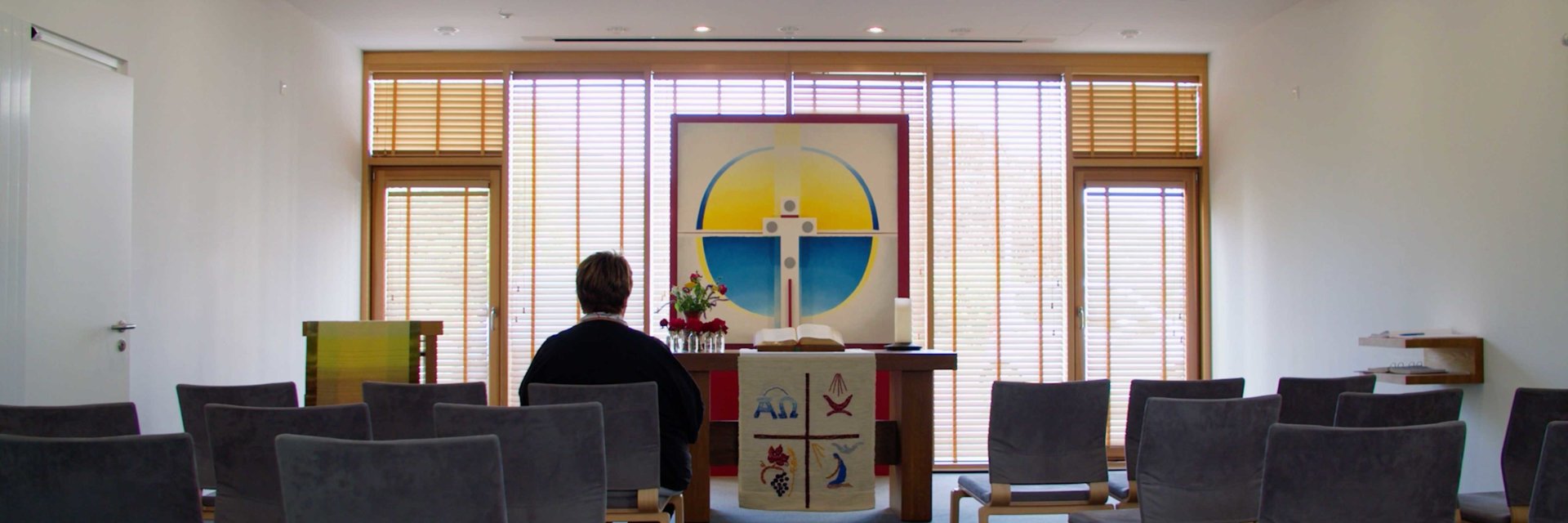 Eine Frau sitzt in der Kapelle, mit friedlicher Stimmung. Man schaut auf den Altar.