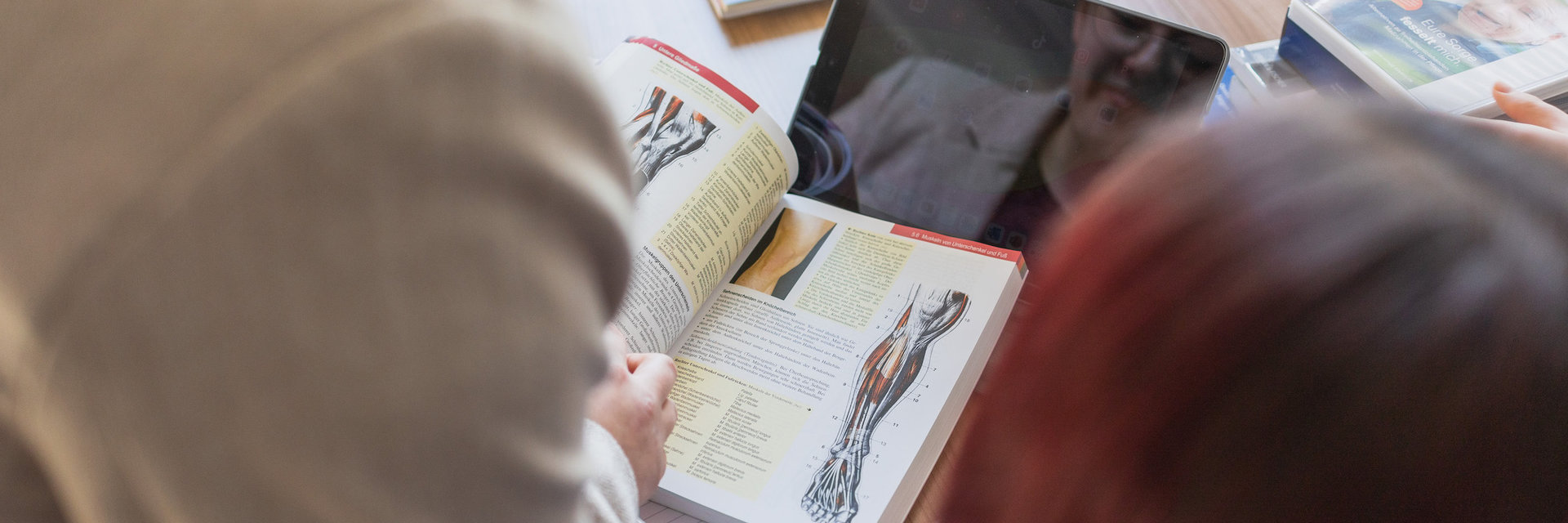 Schüler blättern in einem Buch aus der Pflegeberufsschule