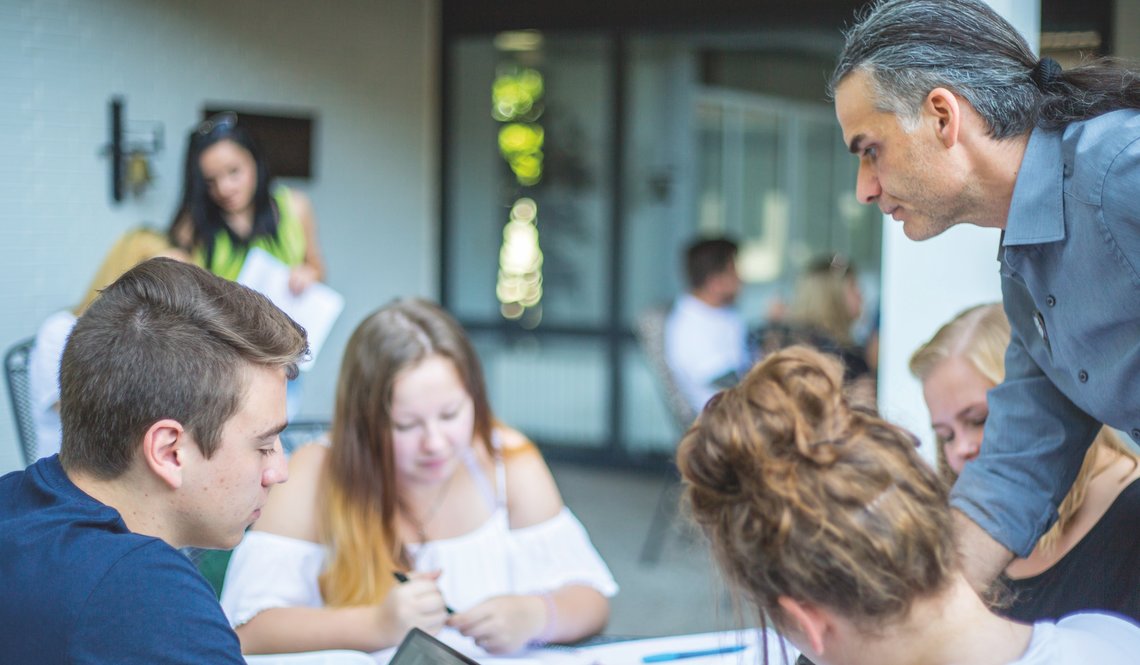 Gruppenarbeit von Schülern, Lehrer hilft