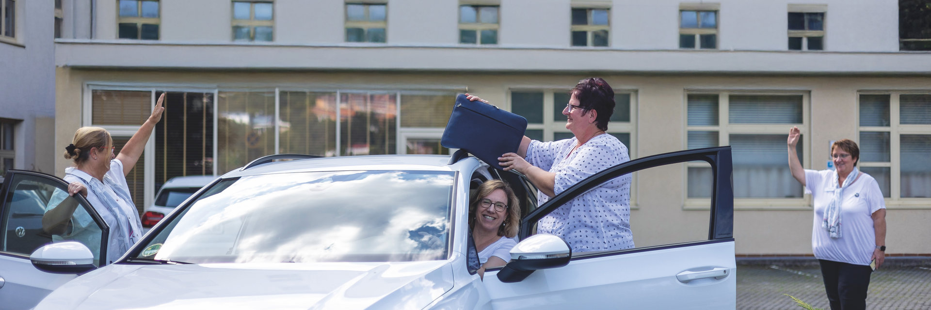 Krankenhaus Mitarbeiterinnen steigen gut gelaunt aus dem Auto und begrüßen sich