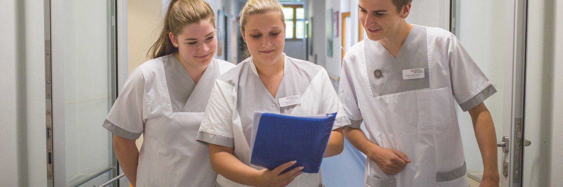 Pfleger besprechen etwas im Gang und schauen auf eine Mappe